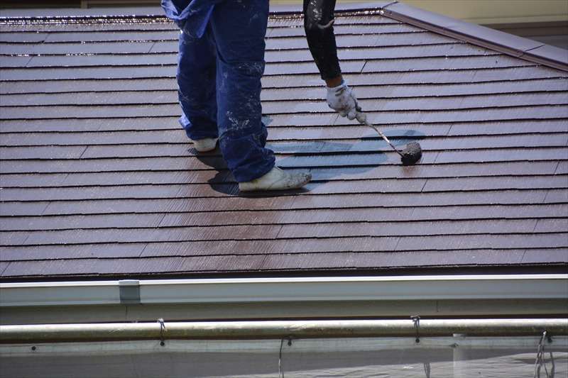 屋根を塗装している人